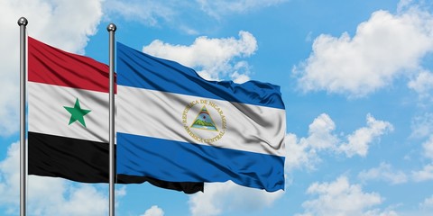 Syria and Nicaragua flag waving in the wind against white cloudy blue sky together. Diplomacy...