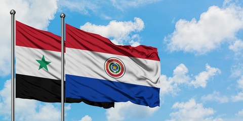 Syria and Paraguay flag waving in the wind against white cloudy blue sky together. Diplomacy...