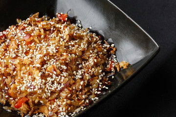 Asian fried rice with eggs, tomatoes, chilli and sesame close-up on a plate, horizontal view from above. Nigerian food party: Jollof rice with fried onion close-up on a plate.