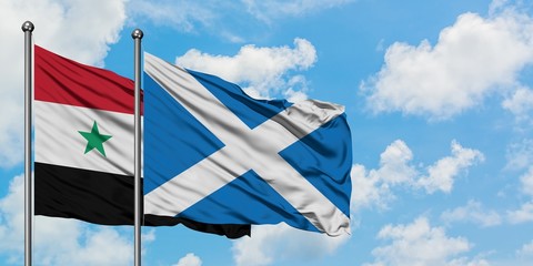 Syria and Scotland flag waving in the wind against white cloudy blue sky together. Diplomacy...