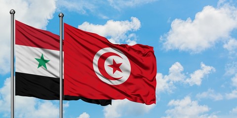 Syria and Tunisia flag waving in the wind against white cloudy blue sky together. Diplomacy...