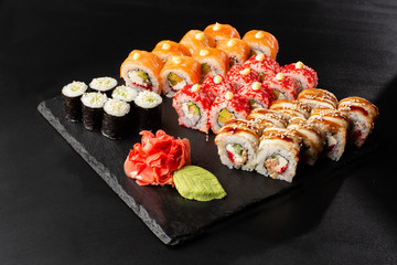 Various kinds of sushi served on black background. Sushi menu for Japanese food. Japanese sushi set. Rolls and maki with salmon, shrimp,eel, crab, caviar and avocado. Horizontal photo