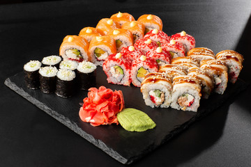 Various kinds of sushi served on black background. Sushi menu for Japanese food. Japanese sushi set. Rolls and maki with salmon, shrimp,eel, crab, caviar and avocado. Horizontal photo