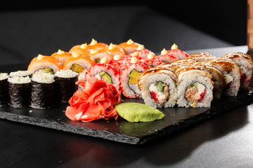 Various kinds of sushi served on black background. Sushi menu for Japanese food. Japanese sushi set. Rolls and maki with salmon, shrimp,eel, crab, caviar and avocado. Horizontal photo
