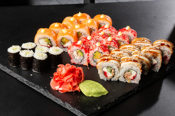 Various kinds of sushi served on black background. Sushi menu for Japanese food. Japanese sushi set. Rolls and maki with salmon, shrimp,eel, crab, caviar and avocado. Horizontal photo
