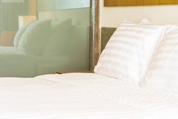 White comfortable pillow on bed decoration with light lamp