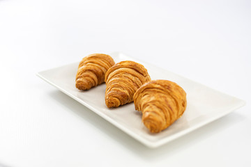 Close-up of three croissants on a plate focused on the center on white background