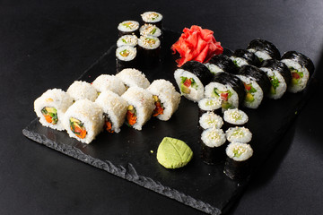 Various kinds of sushi served on black background. Sushi menu for Japanese food. Japanese sushi set. Vegan rolls and maki with carrot, cucumber, tomato and avocado. Horizontal photo