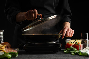 Chef cooks, fries in a pan. Cooking. Smoke and steam under the lid.