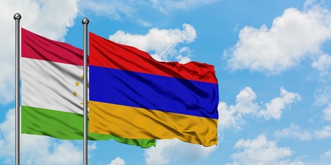 Tajikistan and Armenia flag waving in the wind against white cloudy blue sky together. Diplomacy...