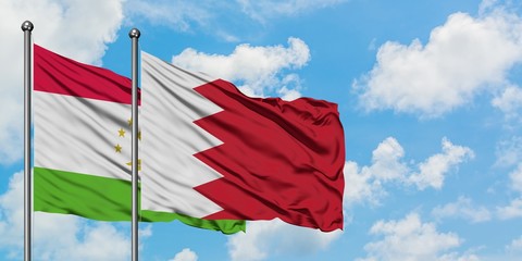 Tajikistan and Bahrain flag waving in the wind against white cloudy blue sky together. Diplomacy concept, international relations.