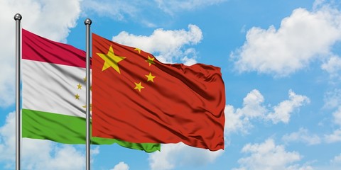 Tajikistan and China flag waving in the wind against white cloudy blue sky together. Diplomacy concept, international relations.