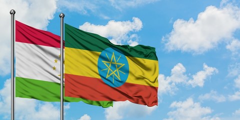 Tajikistan and Ethiopia flag waving in the wind against white cloudy blue sky together. Diplomacy...