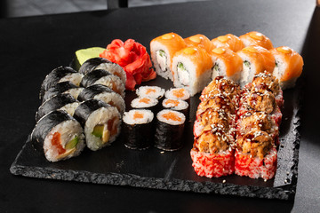 Various kinds of sushi served on black background. Sushi menu for Japanese food. Japanese sushi set. Rolls with tuna, salmon, shrimp, crab and avocado. Horizontal photo.