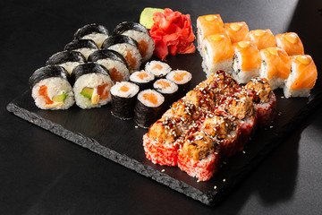 Various kinds of sushi served on black background. Sushi menu for Japanese food. Japanese sushi set. Rolls with tuna, salmon, shrimp, crab and avocado. Horizontal photo.