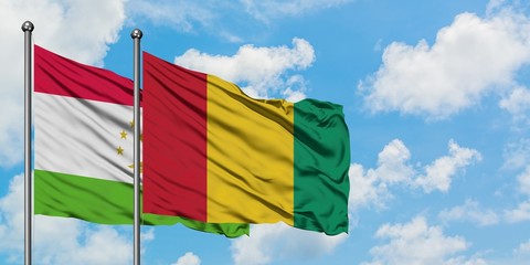 Tajikistan and Guinea flag waving in the wind against white cloudy blue sky together. Diplomacy concept, international relations.