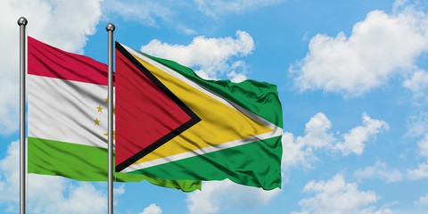 Tajikistan and Guyana flag waving in the wind against white cloudy blue sky together. Diplomacy concept, international relations.