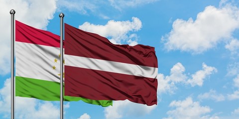 Tajikistan and Latvia flag waving in the wind against white cloudy blue sky together. Diplomacy concept, international relations.