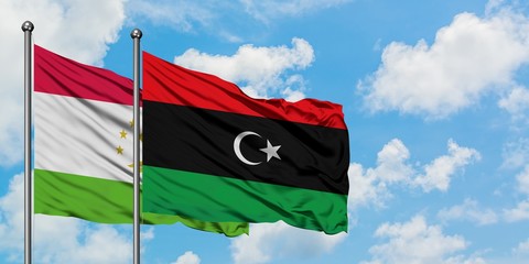 Tajikistan and Libya flag waving in the wind against white cloudy blue sky together. Diplomacy...