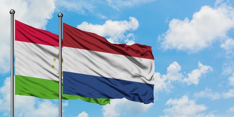 Tajikistan and Netherlands flag waving in the wind against white cloudy blue sky together. Diplomacy concept, international relations.