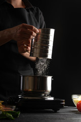 Cooking an Italian bechamel sauce by pouring flour. Freezing in motion. Preparing lasagna. Vertical shot.