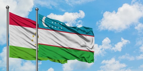 Tajikistan and Uzbekistan flag waving in the wind against white cloudy blue sky together. Diplomacy concept, international relations.