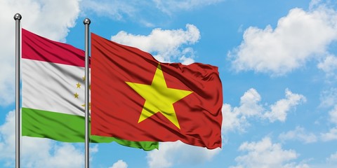 Tajikistan and Vietnam flag waving in the wind against white cloudy blue sky together. Diplomacy concept, international relations.