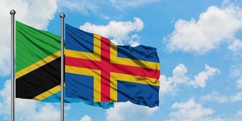Tanzania and Aland Islands flag waving in the wind against white cloudy blue sky together....