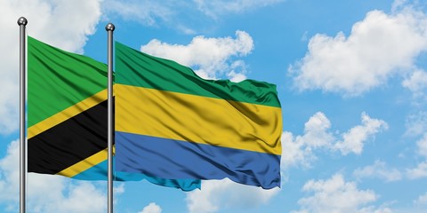Tanzania and Gabon flag waving in the wind against white cloudy blue sky together. Diplomacy...
