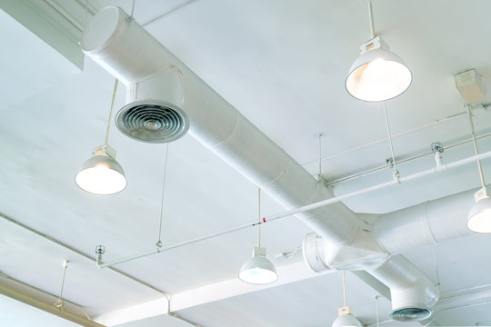 Air duct, air conditioner pipe and fire sprinkler system on white ceiling wall. Air flow and ventilation system. Building interior. Ceiling lamp light with opened light. Interior architecture concept.