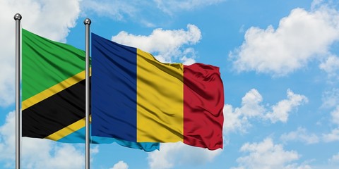 Tanzania and Romania flag waving in the wind against white cloudy blue sky together. Diplomacy...