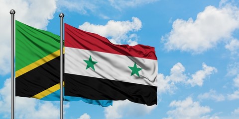 Tanzania and Syria flag waving in the wind against white cloudy blue sky together. Diplomacy...
