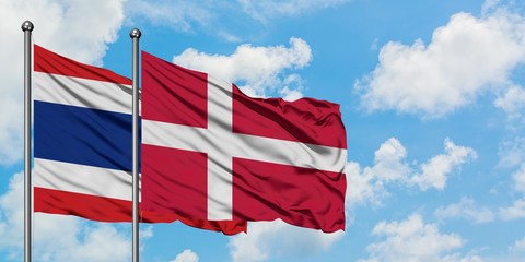 Thailand and Denmark flag waving in the wind against white cloudy blue sky together. Diplomacy...