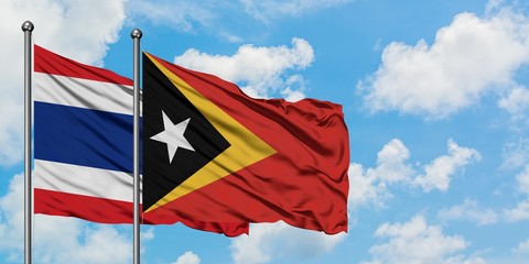 Thailand and East Timor flag waving in the wind against white cloudy blue sky together. Diplomacy concept, international relations.