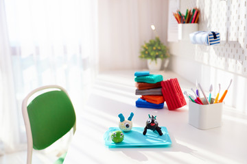 cute creatures, hand crafts made of plasticine by kids, on the desk in the kids room