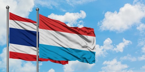 Thailand and Luxembourg flag waving in the wind against white cloudy blue sky together. Diplomacy concept, international relations.