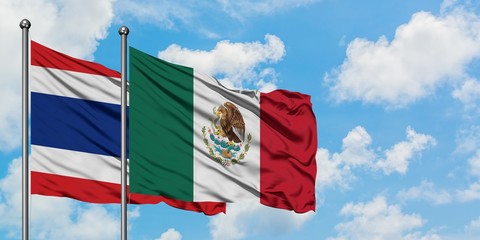 Thailand and Mexico flag waving in the wind against white cloudy blue sky together. Diplomacy...