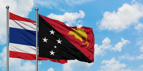 Thailand and Papua New Guinea flag waving in the wind against white cloudy blue sky together. Diplomacy concept, international relations.