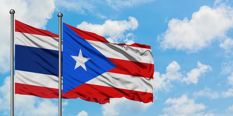 Thailand and Puerto Rico flag waving in the wind against white cloudy blue sky together. Diplomacy concept, international relations.