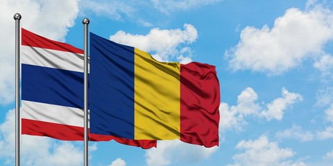 Thailand and Romania flag waving in the wind against white cloudy blue sky together. Diplomacy...