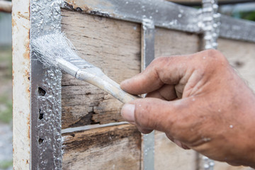 Workers holding a brush painting  the metal frame