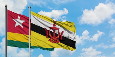 Togo and Brunei flag waving in the wind against white cloudy blue sky together. Diplomacy concept, international relations.
