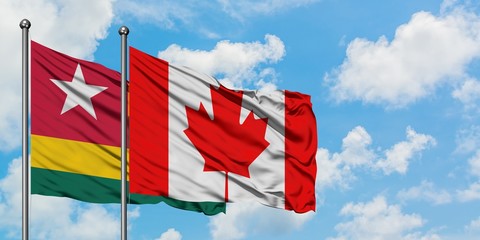 Togo and Canada flag waving in the wind against white cloudy blue sky together. Diplomacy concept, international relations.