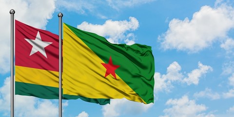 Togo and French Guiana flag waving in the wind against white cloudy blue sky together. Diplomacy concept, international relations.