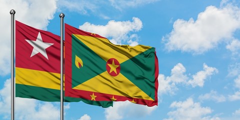 Togo and Grenada flag waving in the wind against white cloudy blue sky together. Diplomacy concept, international relations.