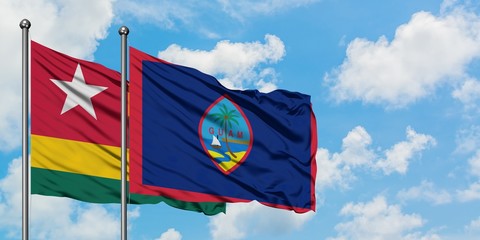 Togo and Guam flag waving in the wind against white cloudy blue sky together. Diplomacy concept, international relations.
