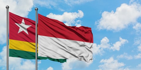 Togo and Indonesia flag waving in the wind against white cloudy blue sky together. Diplomacy concept, international relations.
