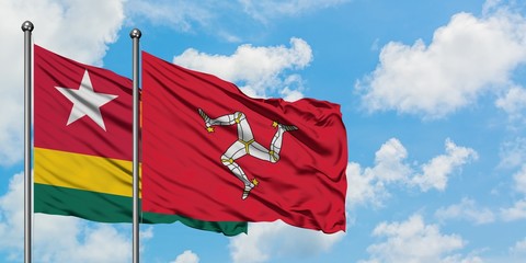 Togo and Isle Of Man flag waving in the wind against white cloudy blue sky together. Diplomacy...
