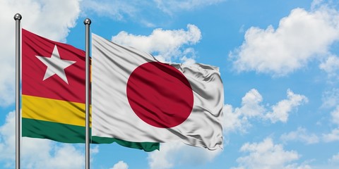 Togo and Japan flag waving in the wind against white cloudy blue sky together. Diplomacy concept, international relations.
