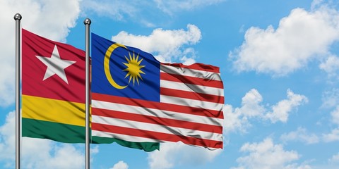 Togo and Malaysia flag waving in the wind against white cloudy blue sky together. Diplomacy concept, international relations.